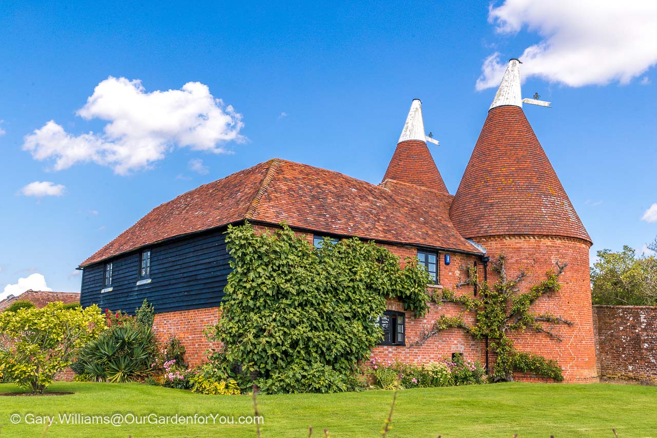 A converted Oast house in Kent with two circular conical roofed towers, topped with a white rotating vent on each
