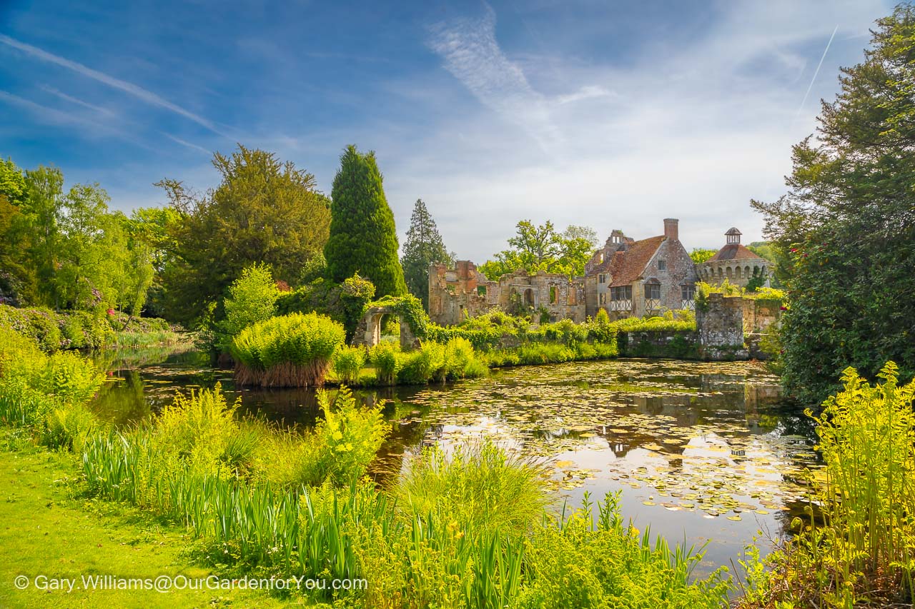 The moat in front of the lush green grounds of the ruins of Scotney Castle