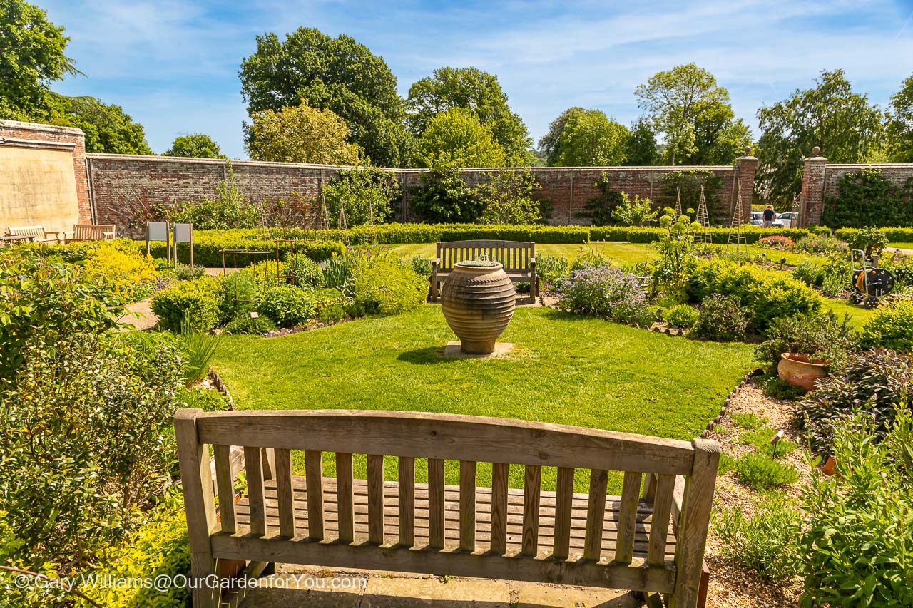 Two benches on either side a smaller herb garden within the more extensive walled Garden at Scotney Castle in Kent