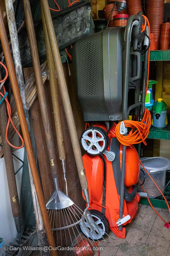 The Flymo EasiStore 340R lawn mower stored upright within our potting shed.