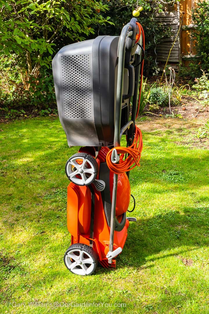 The Flymo EasiStore 340R lawn mower is prepared for storage in an upright position on the lawn.