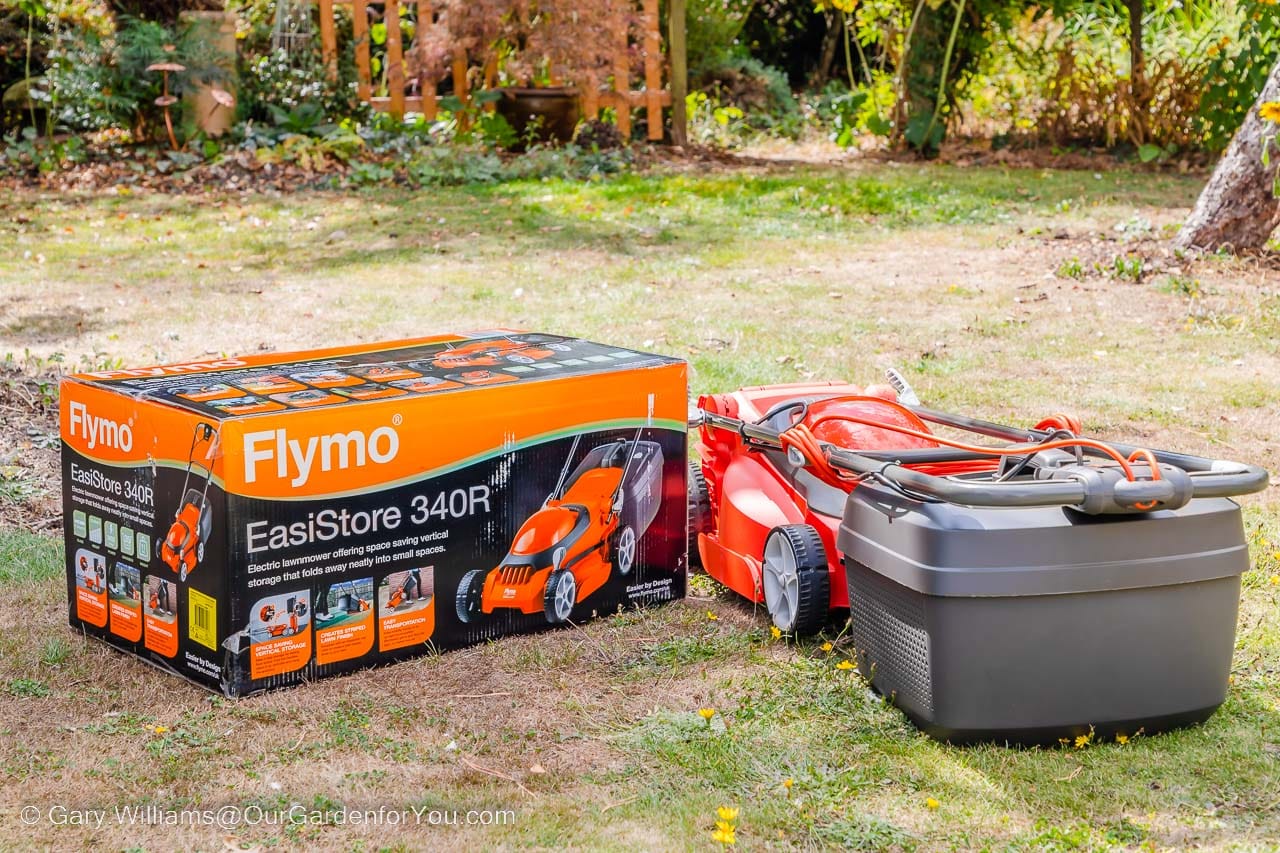 The Flymo EasiStore 340R folded flat next to the box it came it on our lawn