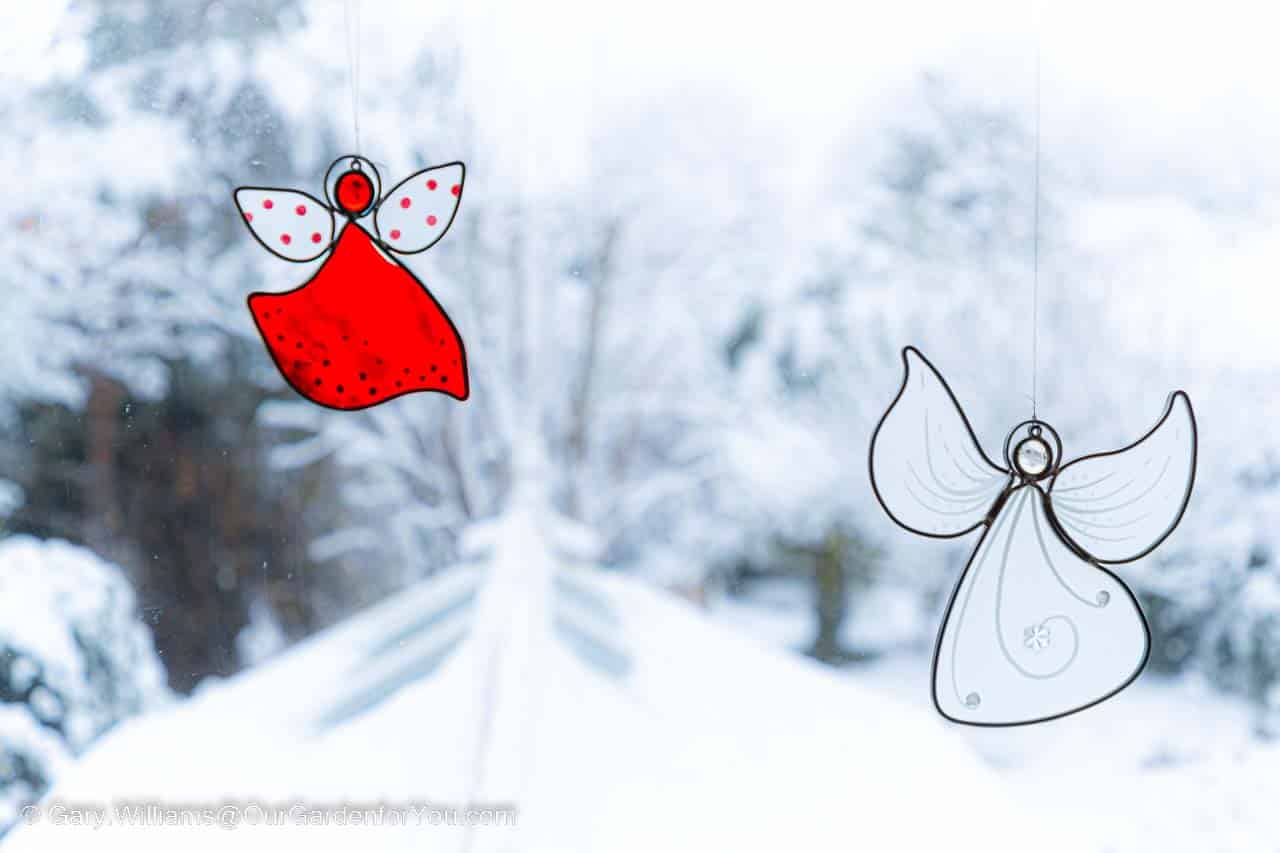 Two glass angel decorations on a window overlooking our snow covered garden.