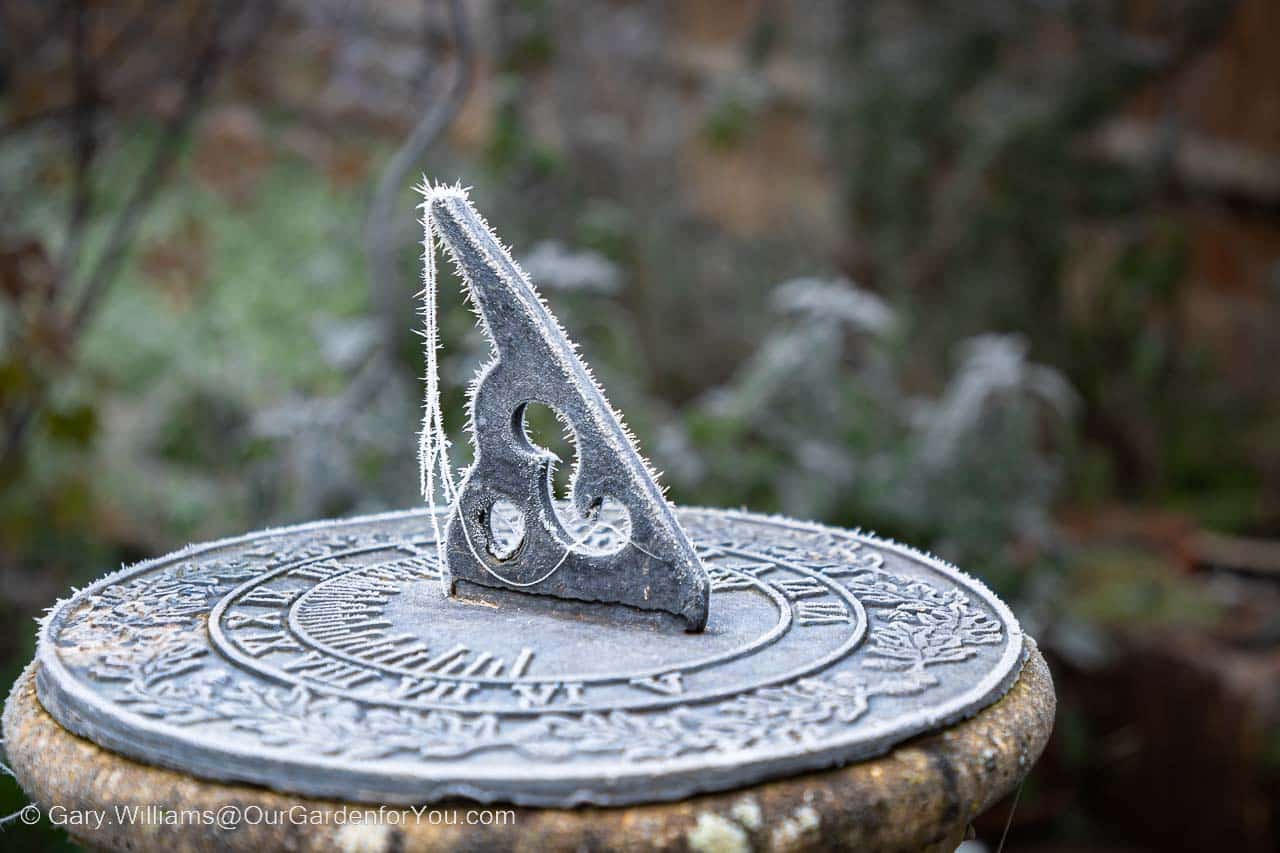Our sundial, complete with cobwebs, mounted on a stone plynth, after a heavy frost in winter