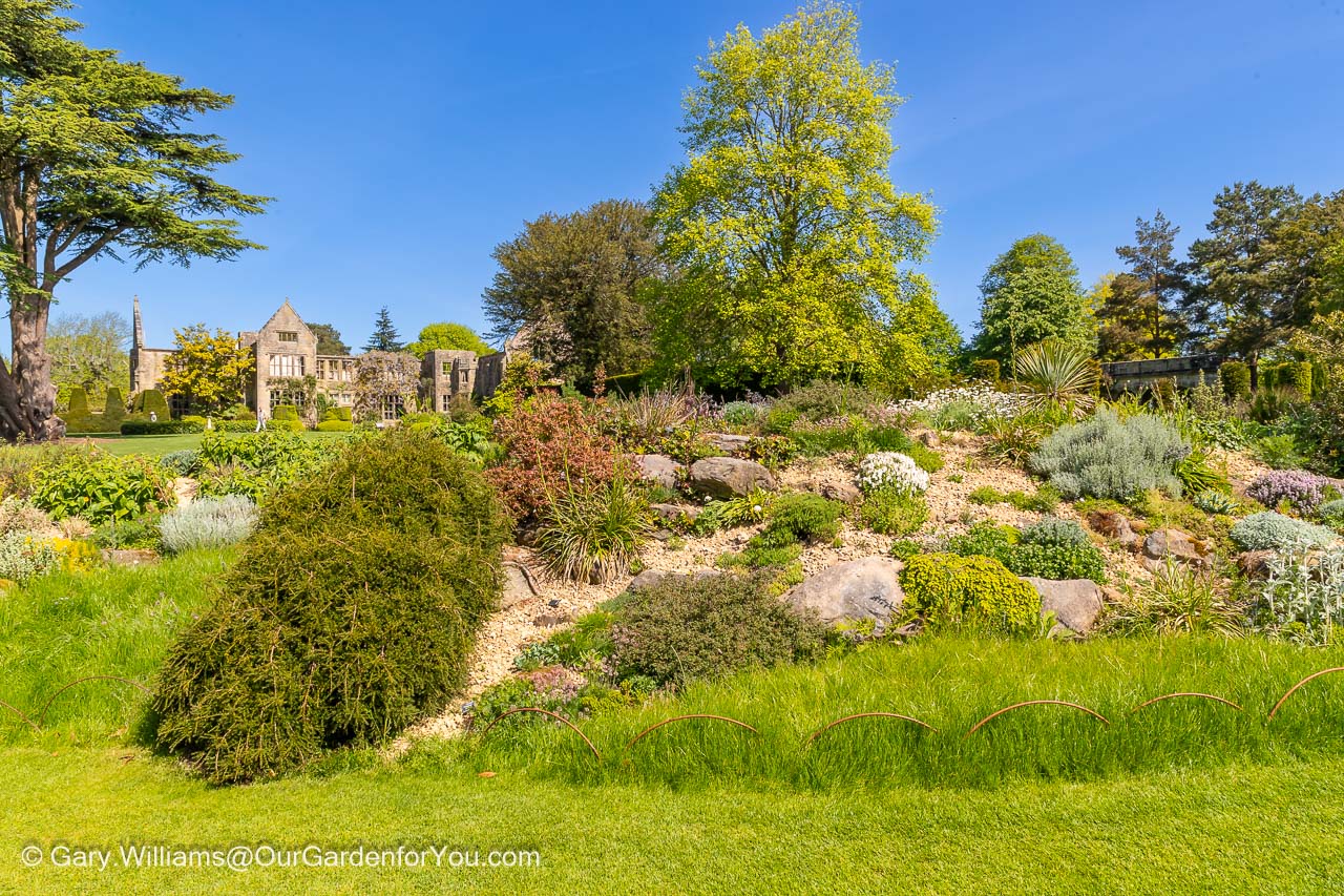 Another view from the rockery of the ruined national trust nymans house on a bright day under a blue sky
