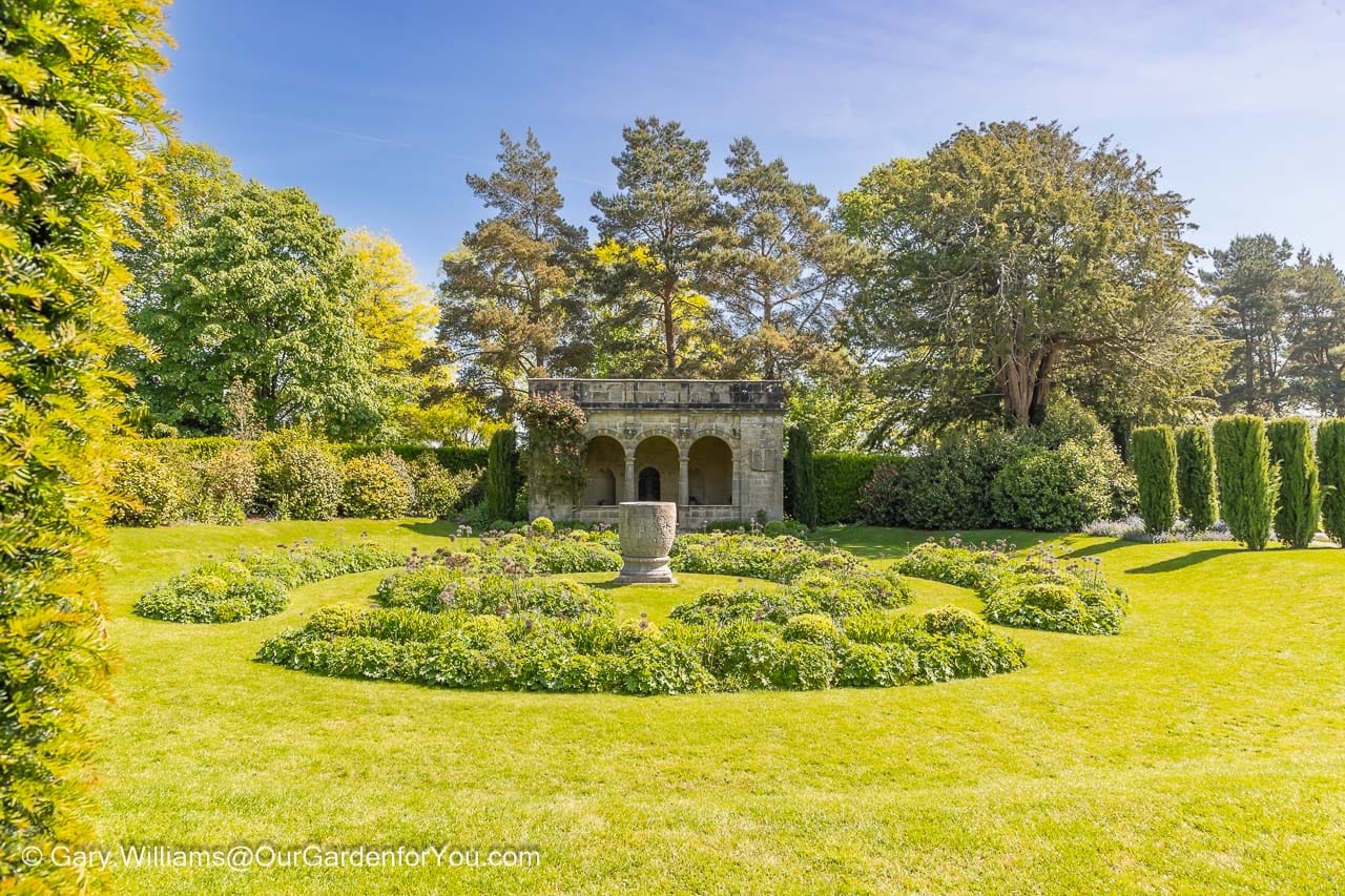 A circular sunken garden in front of a stone loggia at nymans house and gardens in west sussex