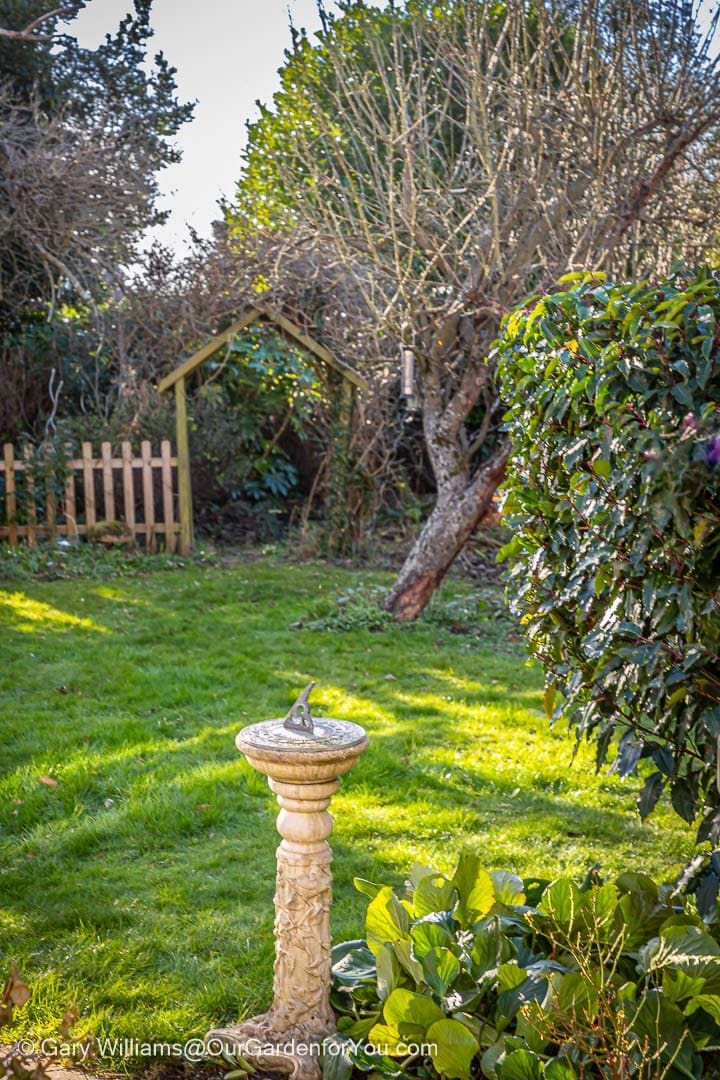 A view of the yet to be mown lawn, in february, from the sundial to the arch and beyond in our garden